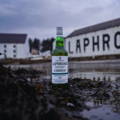 Bouteille de Single Malt Scotch Whisky posée sur des algues devant la distillerie Laphroaig sur l'île d'Islay dans les Hébrides intérieures d'Ecosse