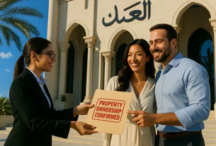 Real estate agent hands a 'PROPERTY OWNERSHIP CONFIRMED' document to a smiling man and woman outside a building with arches and Arabic script, celebrating a successful property purchase.