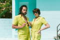 a man and a woman model matching chartreuse jumpsuits on the pool deck for poolside pride: a slim aarons-inspired pride campaign
