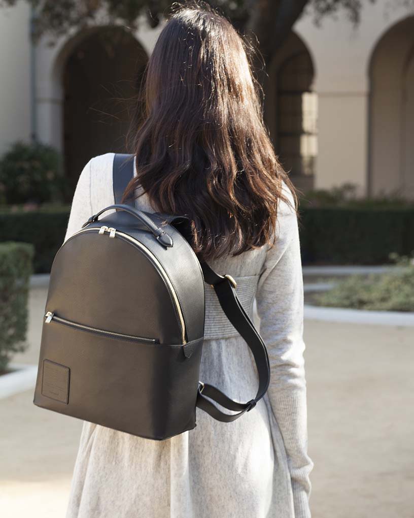 Woman in grey dress carrying an Opus Mind black bag to go to the university