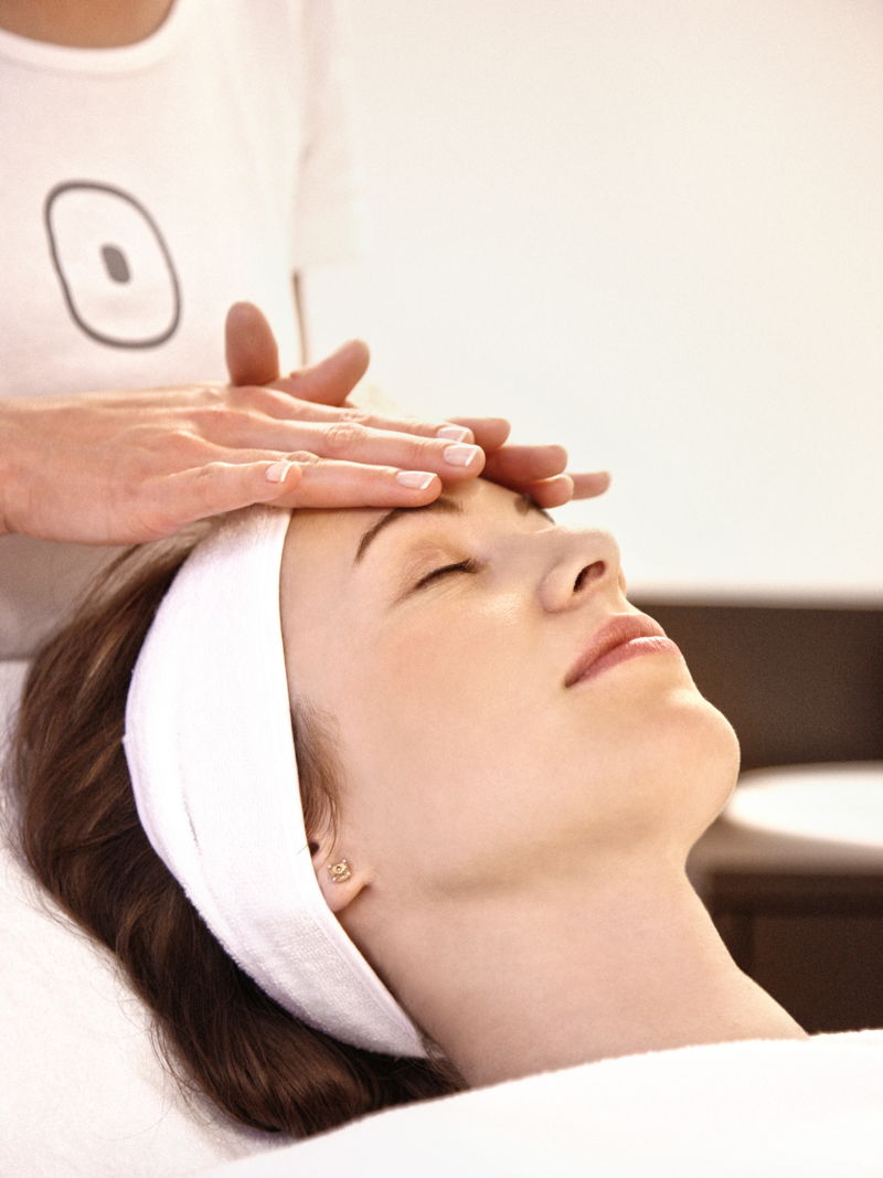 Masseurin legt Frau Hände aufs Gesicht beim Spa-Treatment