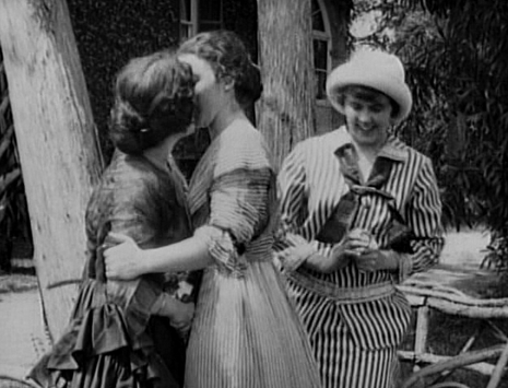 Image of a same sex kiss in "A Florida Enchantment" the image is in black and white, with the women wearing long dress suits.