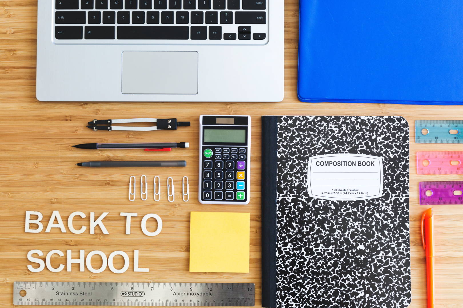 Articole de papetărie, laptop și carte de compoziție pe un fundal din lemn cu textul 'Back to School' - pregătiri pentru noul an școlar