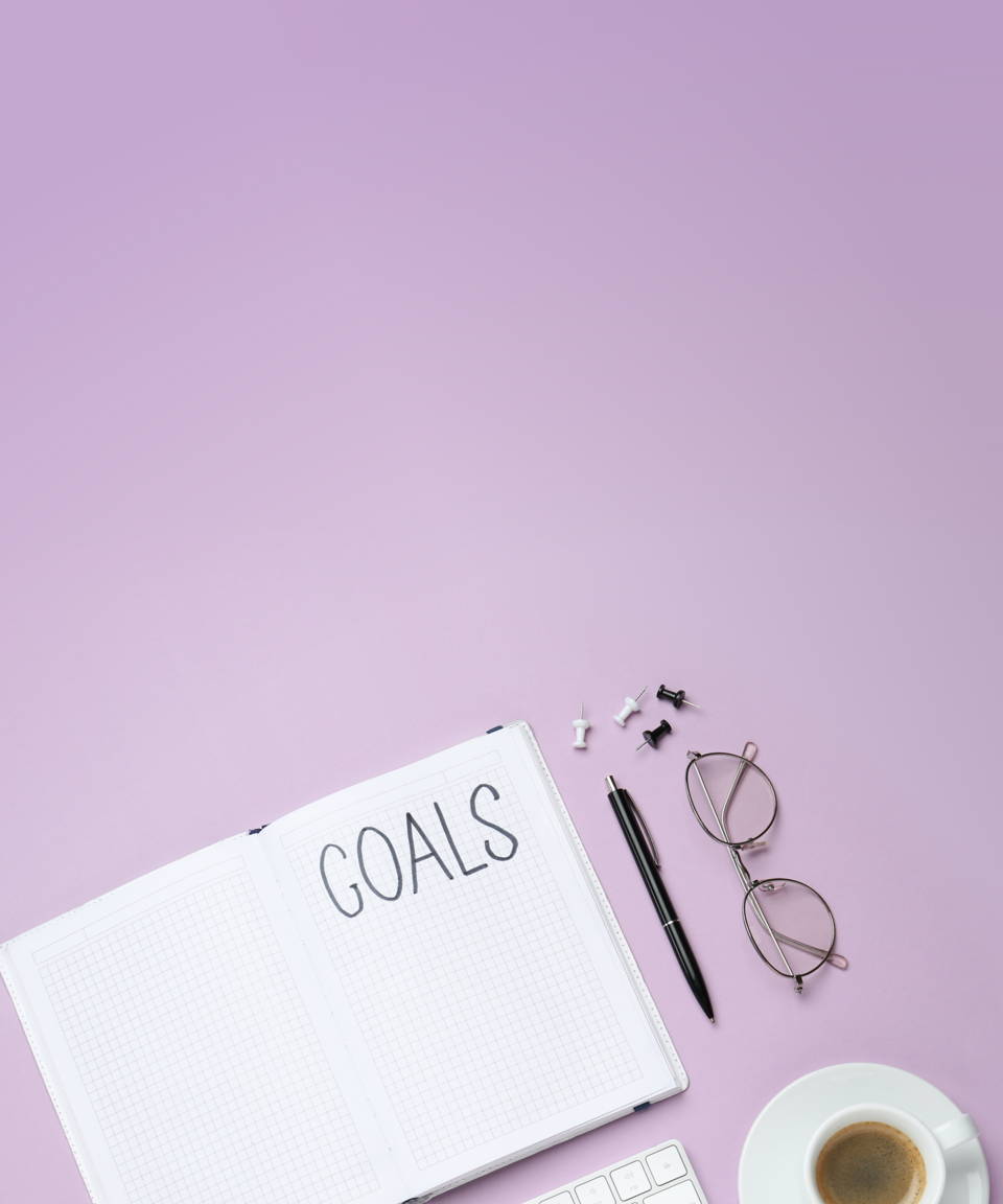A notebook that says "goals" next to a cup of coffee, thumbtacks, a pen, and a pair of glasses for Confetti's Virtual Vision Board Workshop