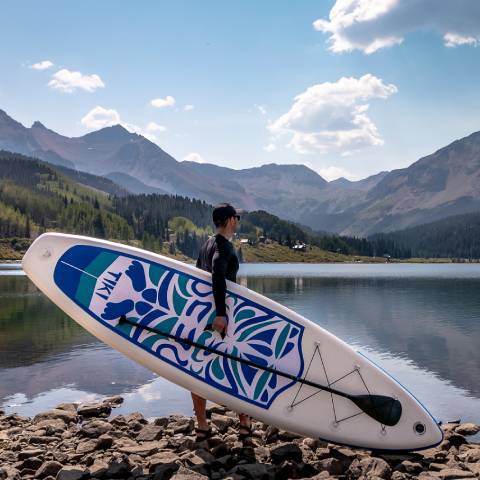 Customer handling blue TIKI best canadian inflatable paddle board towards Vancouver lake