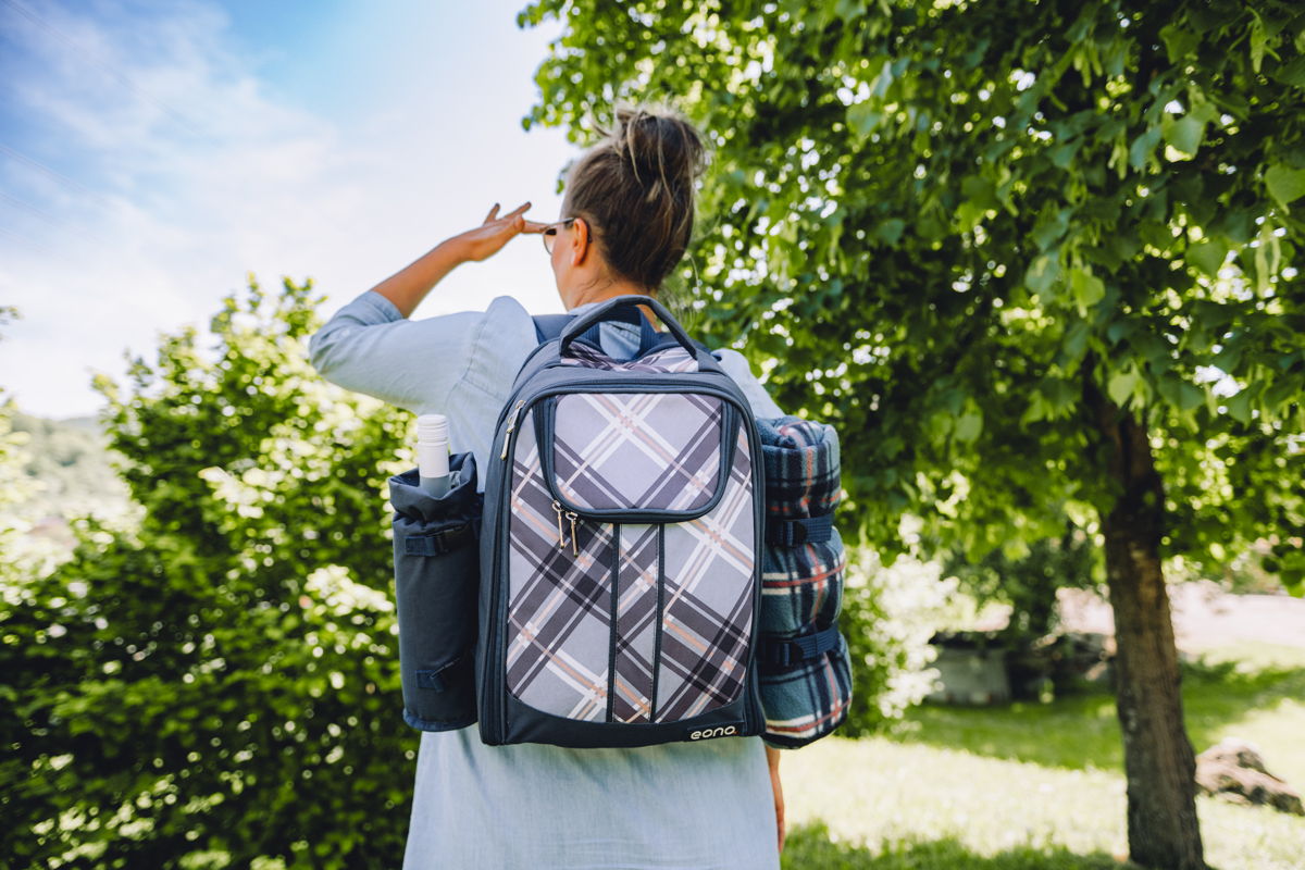 Frau hat den Picknick-Rucksack auf dem Rücken und sieht in die Ferne