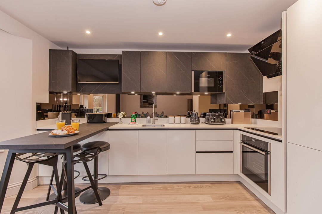 Large kitchen with breakfast bar, white cabinets paired with black paint