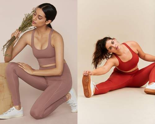Woman wearing pale rose pink crop sports bra and matching high waisted leggings with white velcro trainers holding some flowers and woman wearing white trainers with gum soles and bright red matching cropped sports bra and leggings from sustainable activewear brand Girlfriend Collective