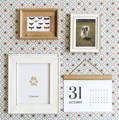 Four framed items on a patterned wall: a butterfly collection, a dog photo, a paw print labeled "Conan," and a calendar showing December 31.