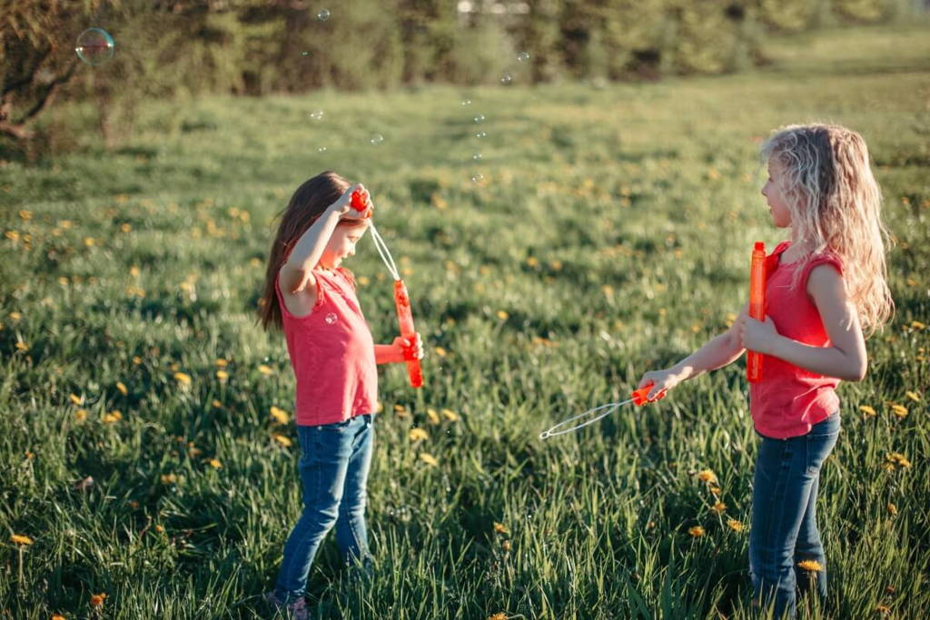 Two girls blowing bubbles in the park.