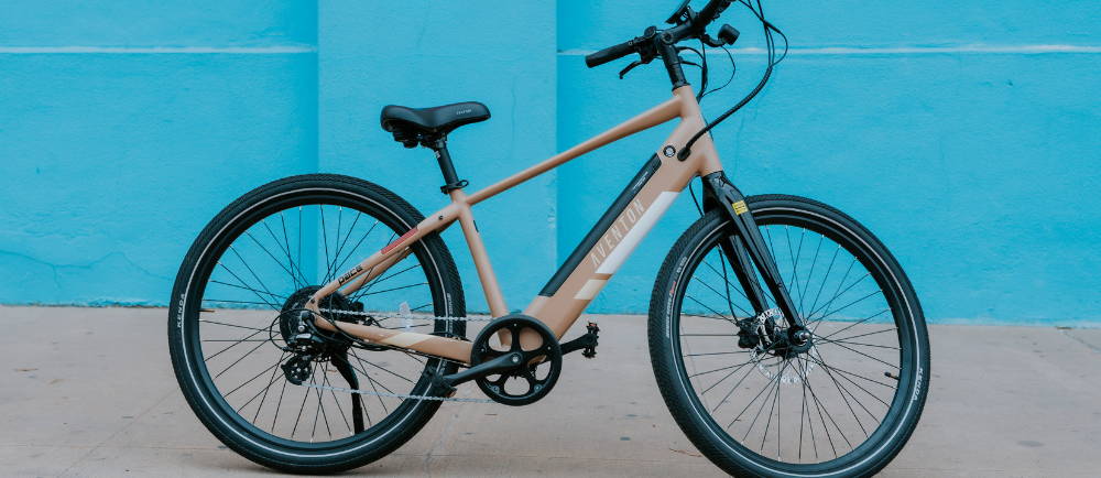Aventon Pace electric bike on sidewalk in front of blue wall