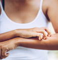 a female scratching her arm; hyaluronic acid may improve symptoms of eczema