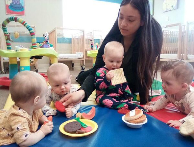 Babies with plastic toy food on the floor with a teacher