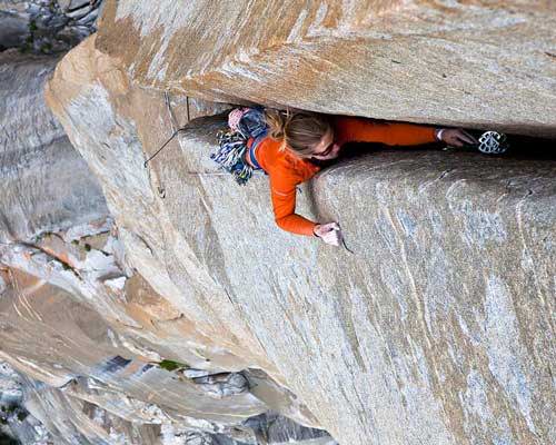 Woman wearing Patagonia sustainable climbing clothing in a crack in Yosemite