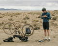 Cycliste réparant un pneu crevé sur son vélo gravel électrique.