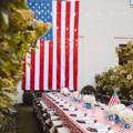 red and white checkered tablecloth on a banquet table outdoors with a huge american flag hanging on the background