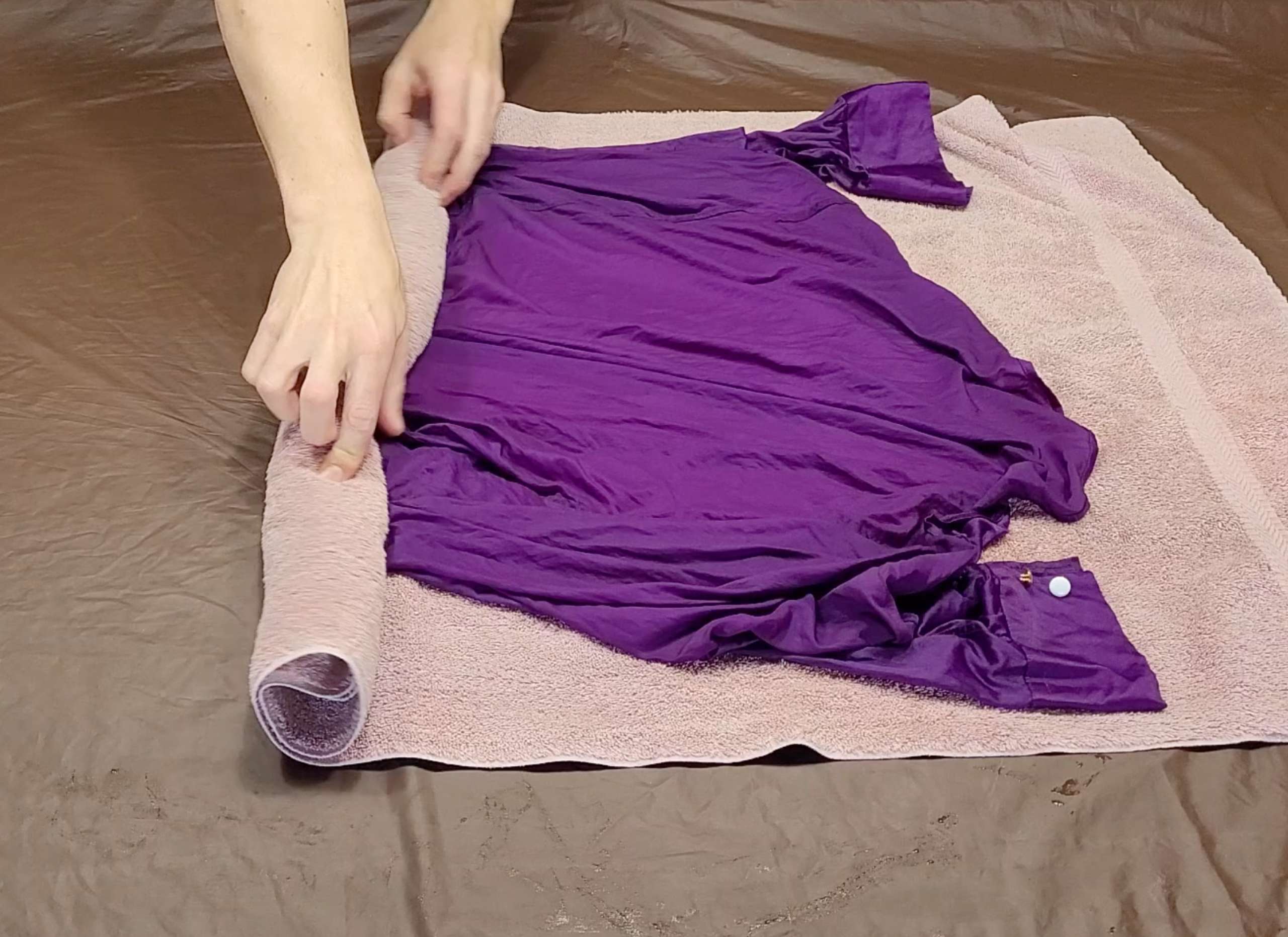 photo of a wet satin garment being rolled in a soft towel