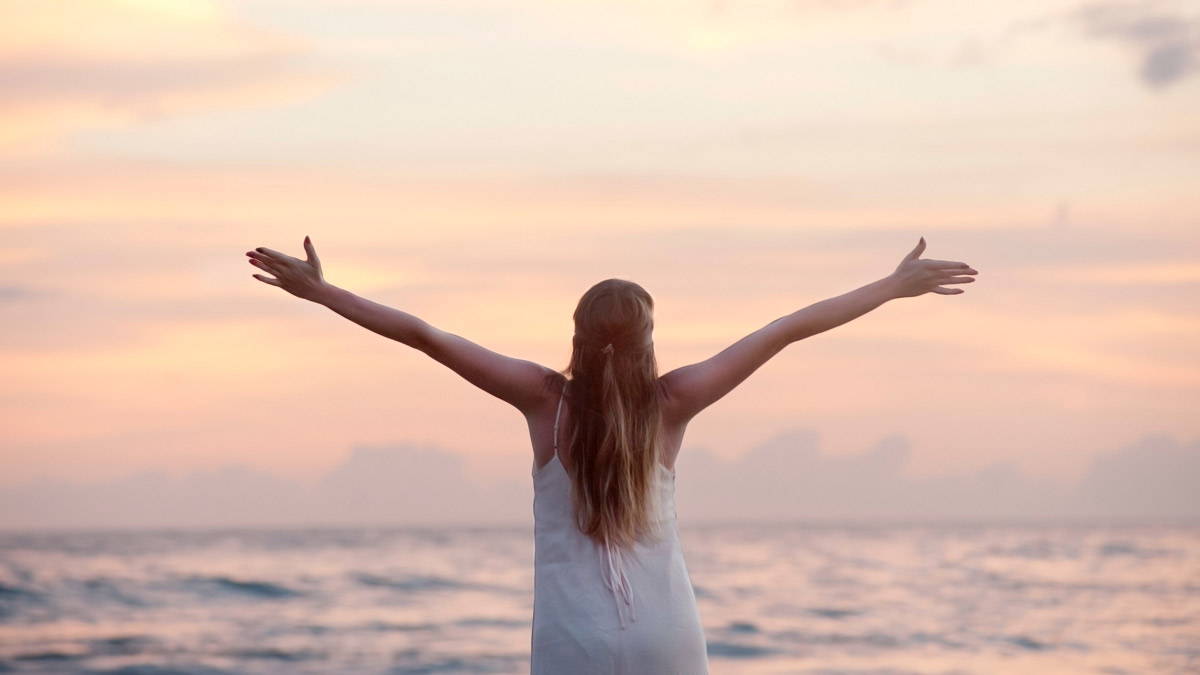 A happy and healthy woman looking out to a peaceful sea and sky