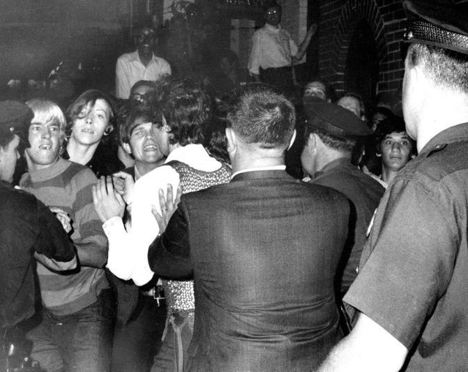 A large group of atendees are being pushed by the police. Black and white image.