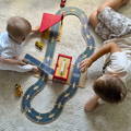 Two boys playing with a Montessori Track Builder Kit featuring wooden cars, garage, and race tracks.
