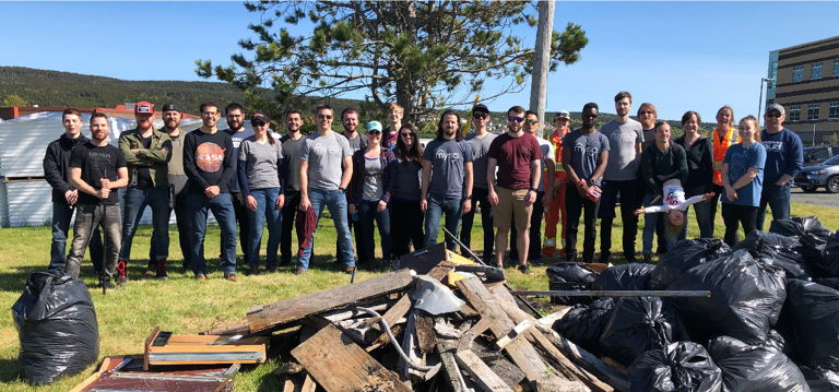 Mysa employees standing behind a large pile of filled garbage bags, scrap wood, and recyclables