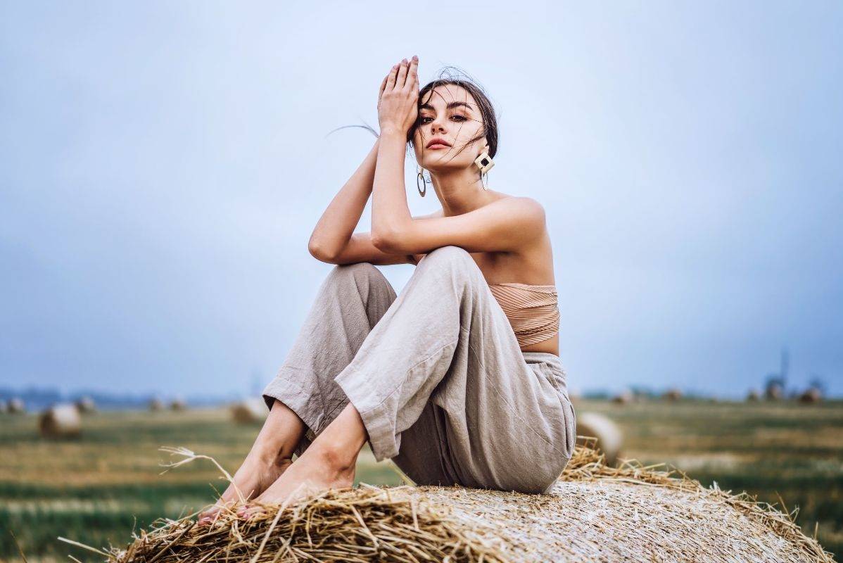 barefoot-girl-in-linen-pants-sitting-on-a-haystack