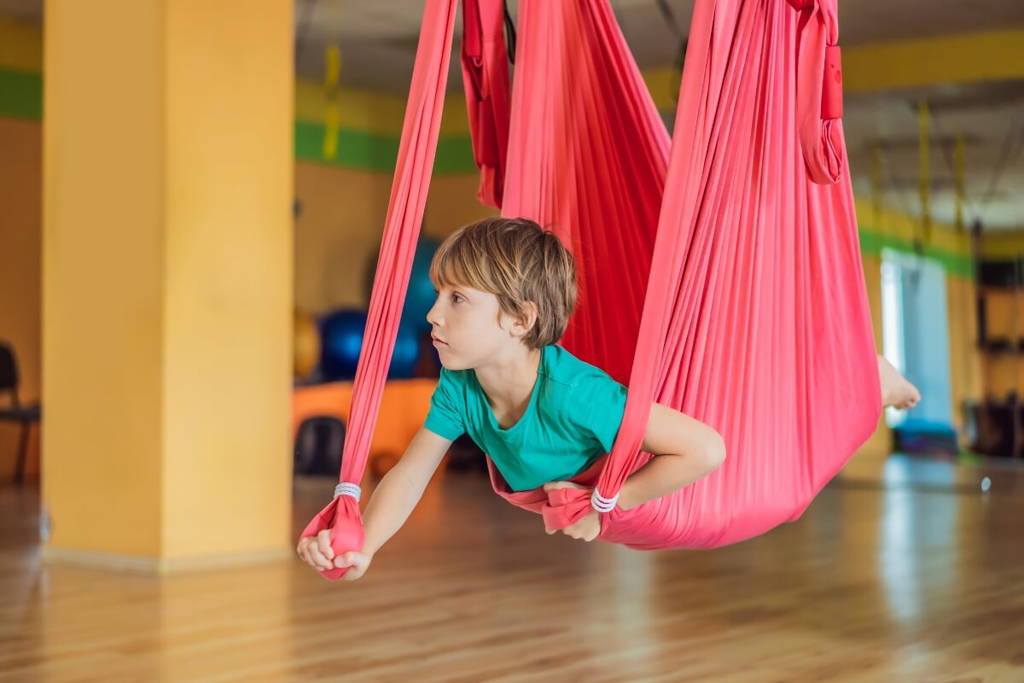 Boy laying in a pink sensory swing.