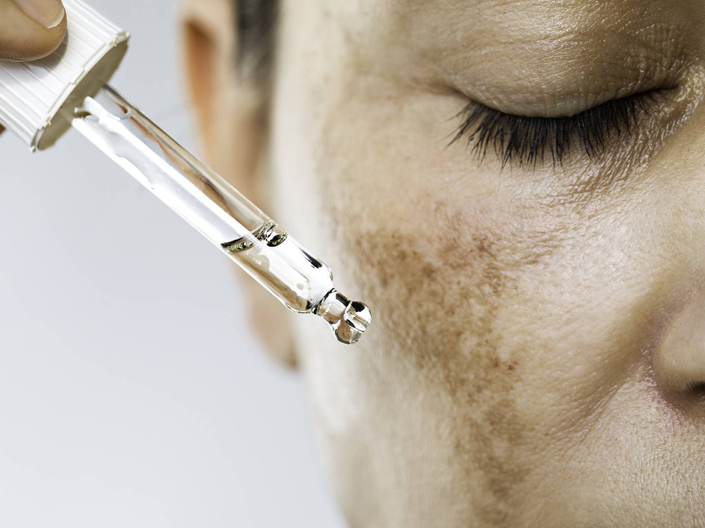 Woman applying serum on her face 