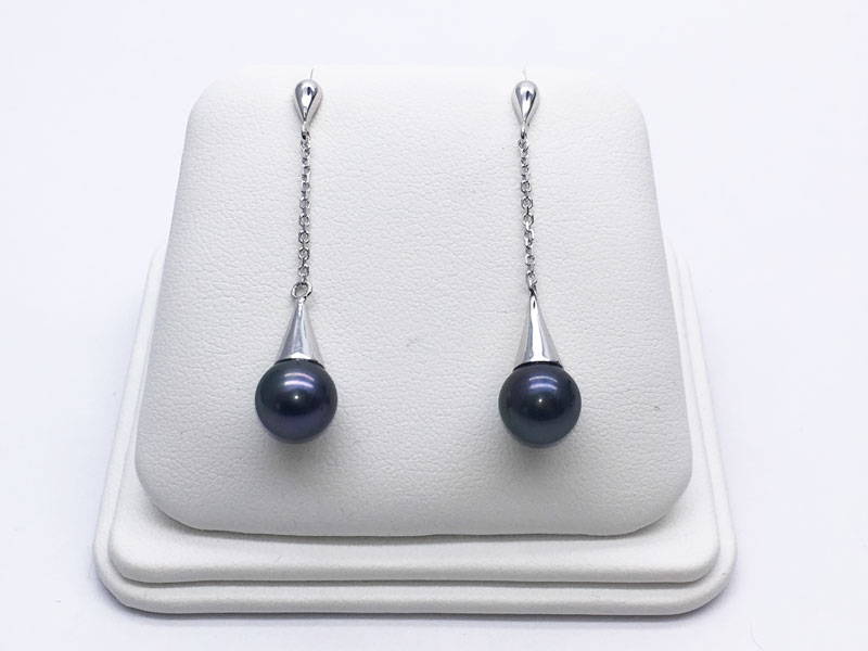 White gold handmade pendant earrings with black beads on a jewellery display stand