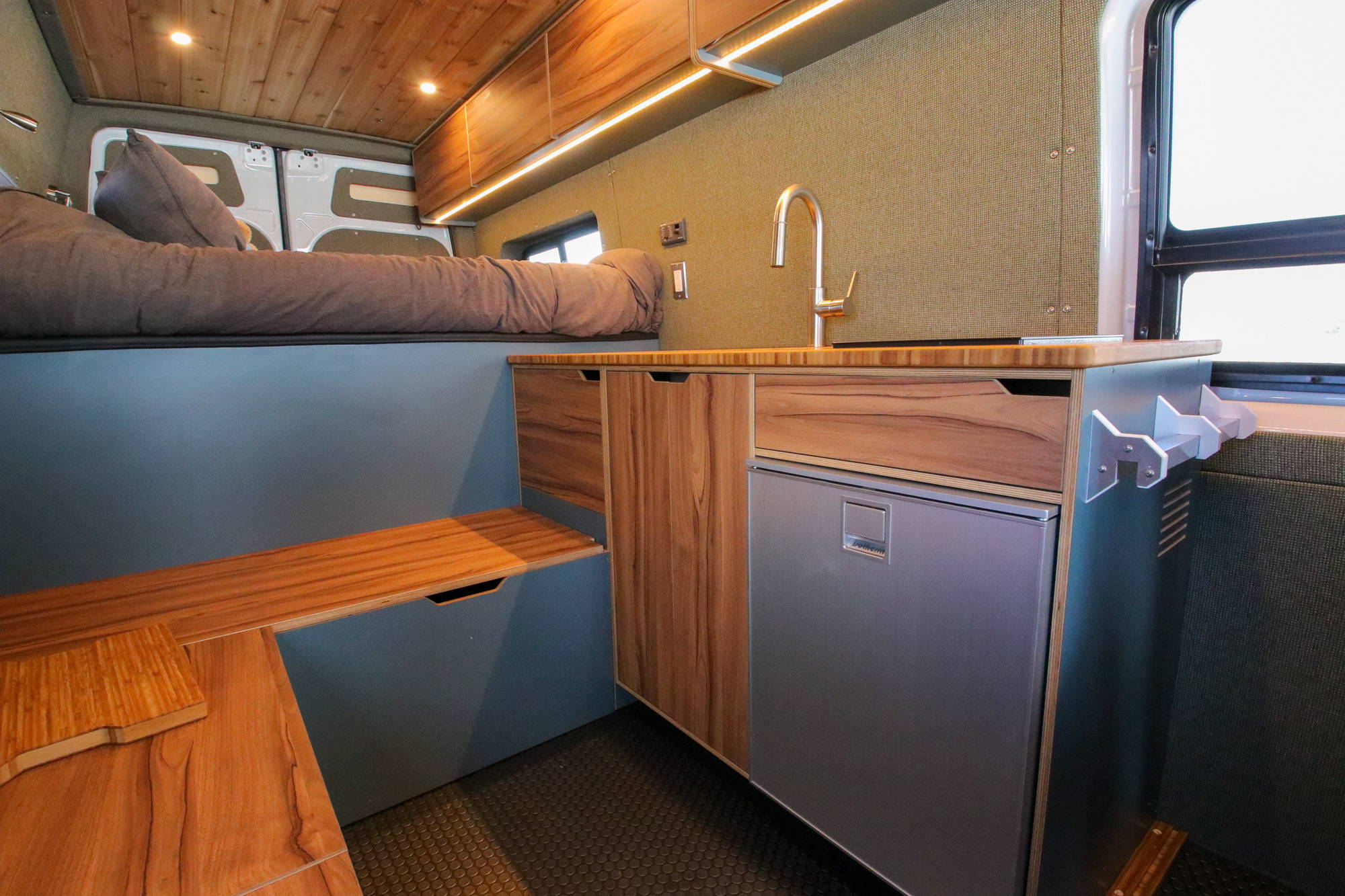 Rack & Roll - Sprinter 144 Conversion Van - Man in Under-Bed Storage Area with Shelves - The Vansmith