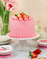 A finished, frosted vegan strawberry shortcake cake, on the table and ready to be sliced.