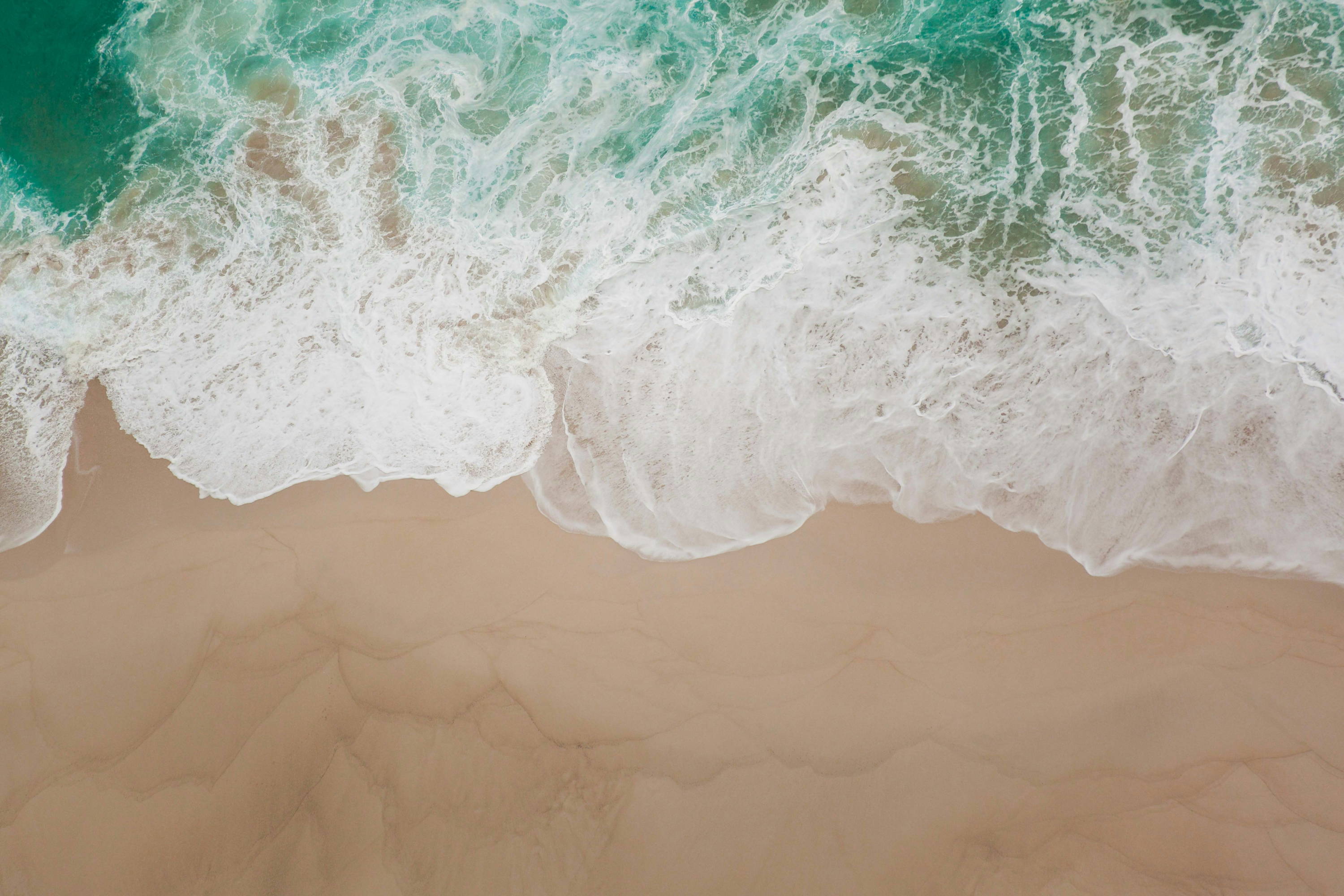 Wave coming up on a sandy beach.