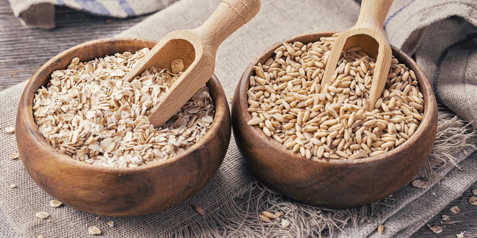 Two wooden bowls filled with raw grains.