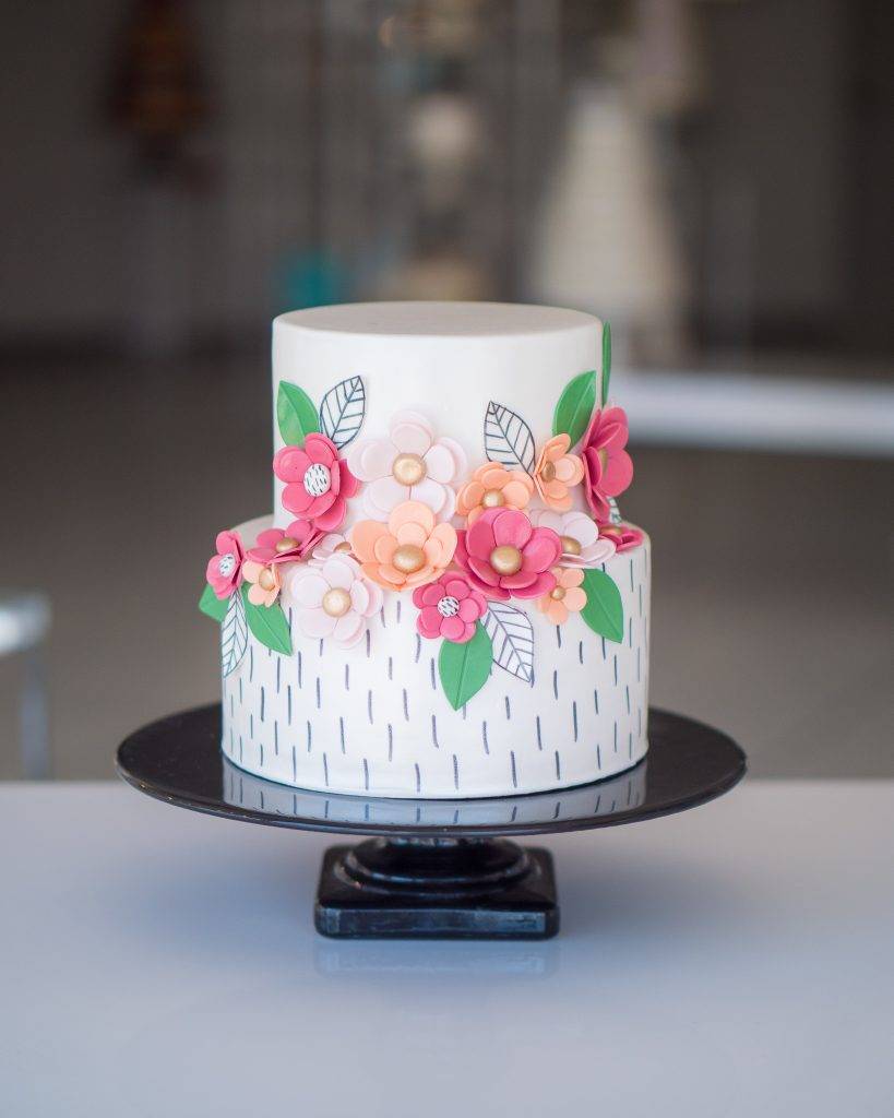 Flower cake made of fondant with white icing and pink and peach flowers. Order your cake today at our bakery for birthdays or special occasions at House of Clarendon in Lancaster, PA