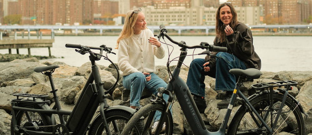 Two women sitting next to electric bikes