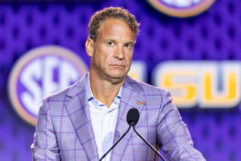 Image may contain: Lane Kiffin, Crowd, Person, Electrical Device, Microphone, Press Conference, Clothing, Shirt, and Adult