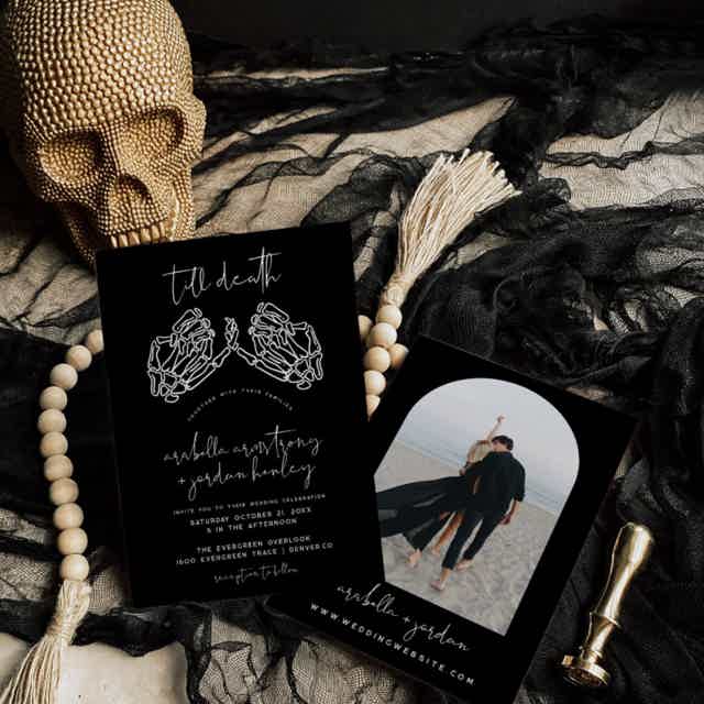 Gothic wedding invitation with skeleton hands in pinky promise pose. Calligraphy font spells 'Till Death' at the top. Set Halloween wedding styled photoshoot