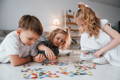 Siblings playing with puzzles on their playroom floor.