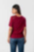 A woman wearing a maroon short-sleeve top with lace details on the shoulders and blue jeans, shown from the back against a white background.
