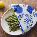 A white plate with asparagus on it covered in a white and blue towel with bears on it