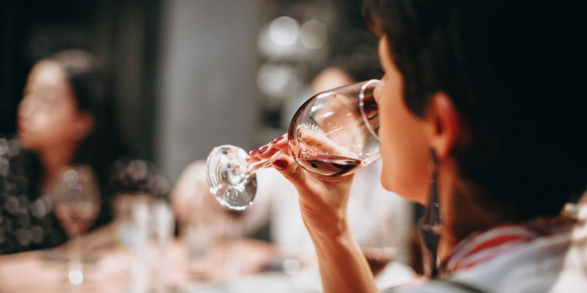 Woman taking a sip of the end red wine highlighting the importance of sipping while wine tasting. 