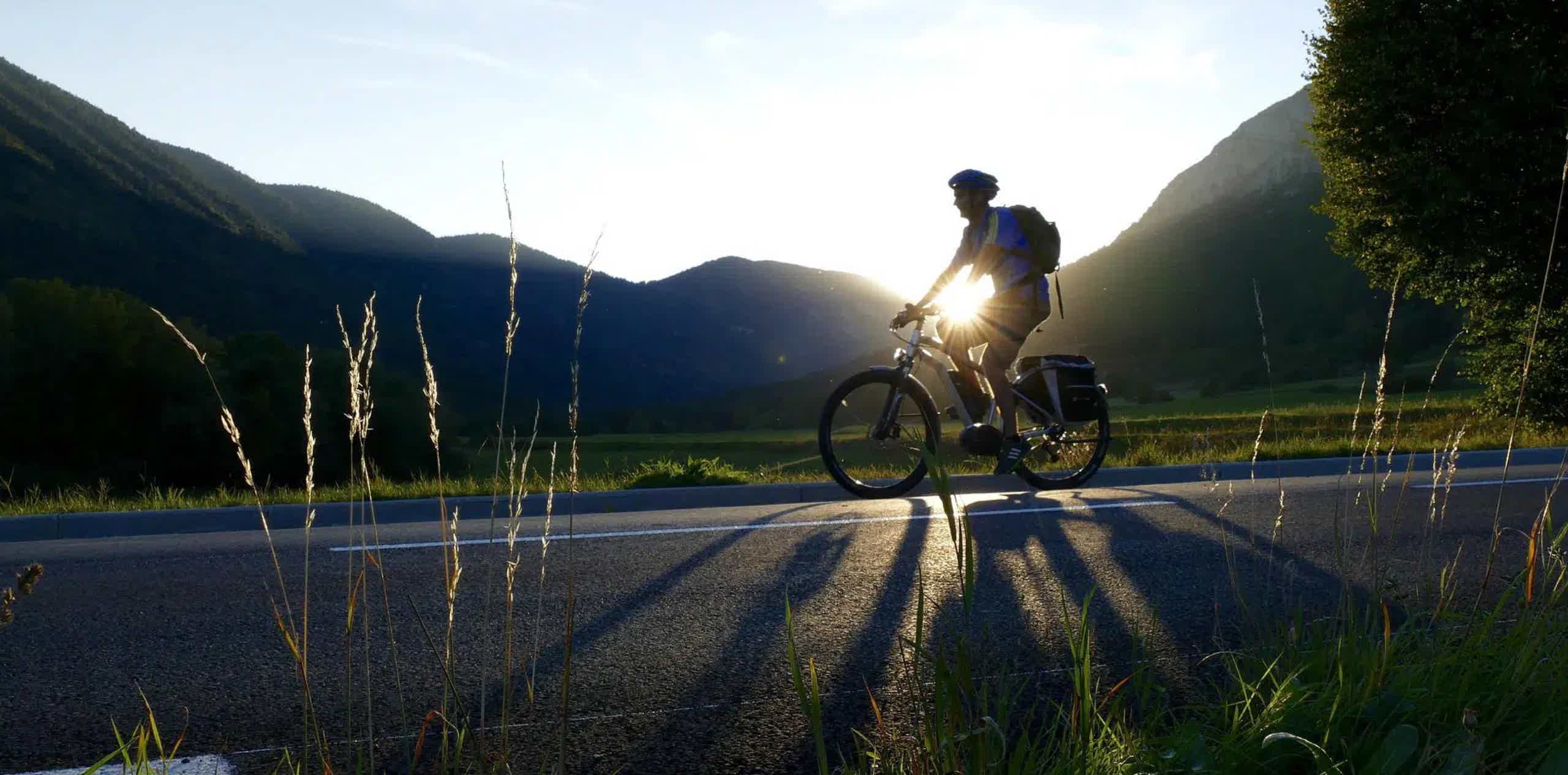 Imagen de recurso de una persona rodando con una e-bike y, al fondo, cayendo el sol en un entorno rural.
