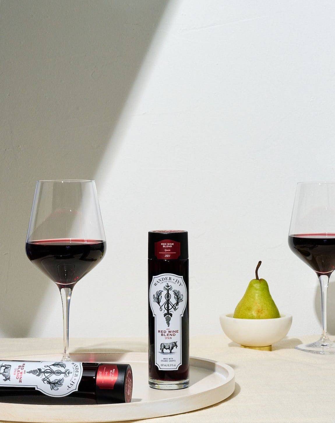 A display of single-serve bottles of Red Wine Blend on a tray with a wine-filled glass