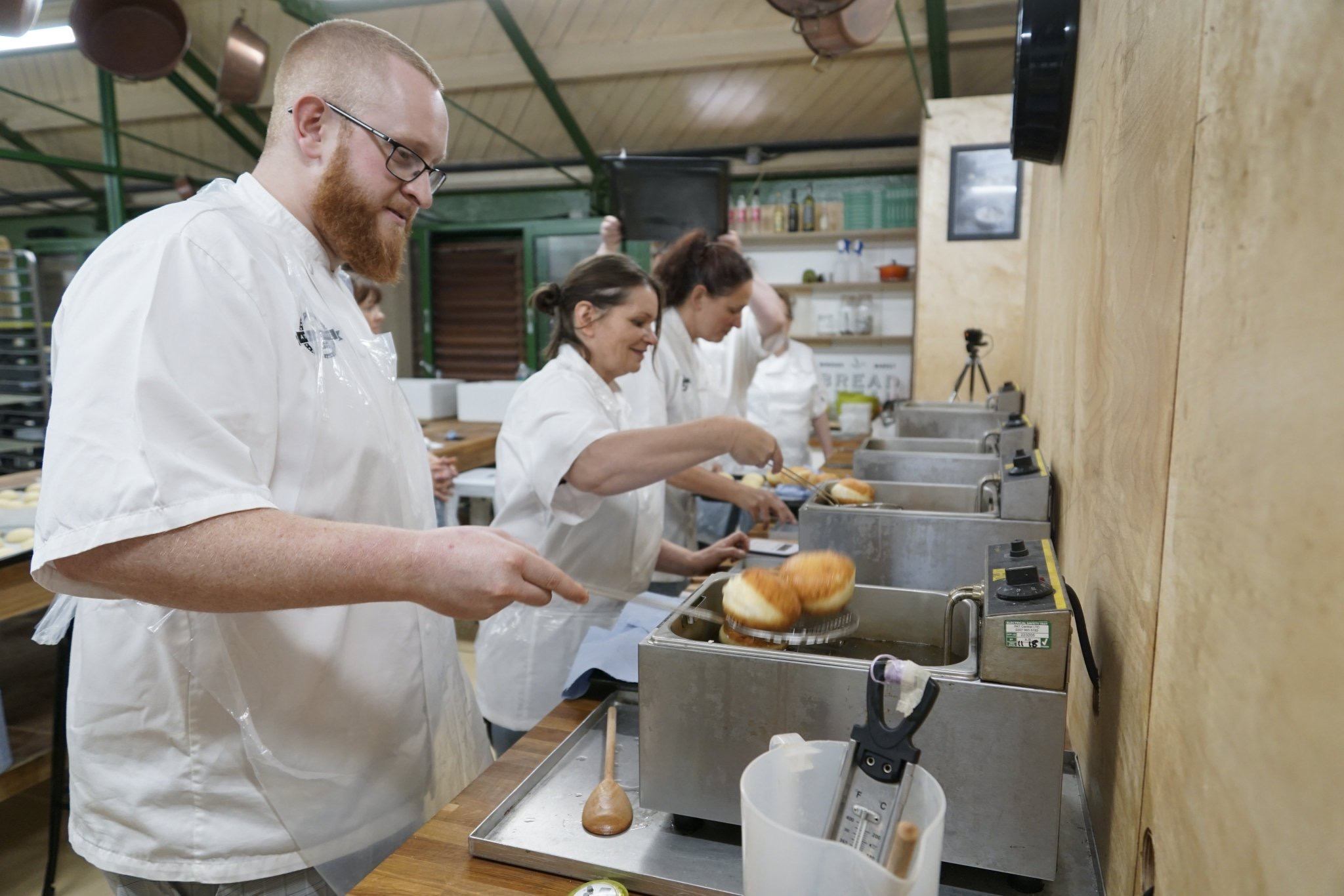 Group kitchen with one male and two female chefs making food.