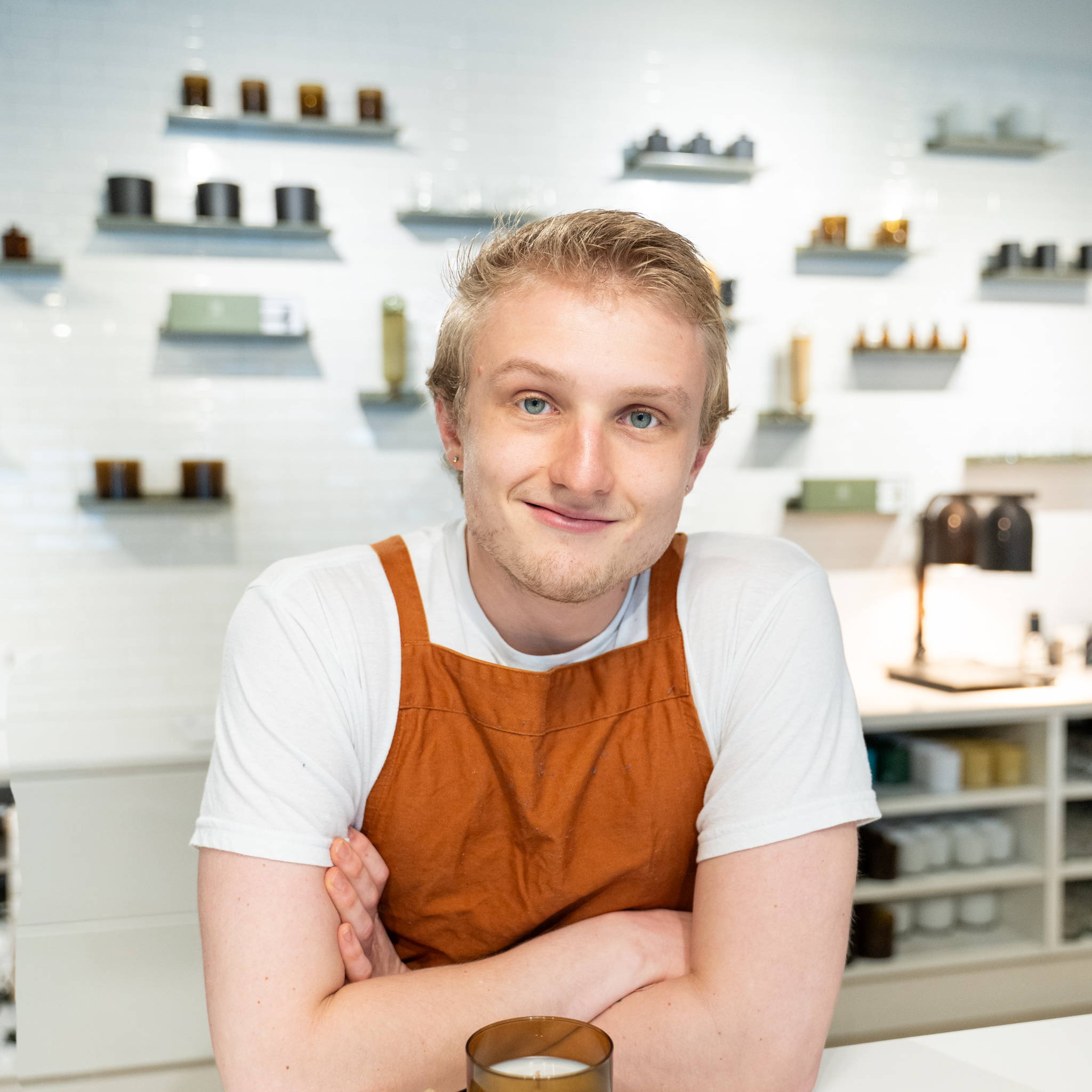 male in orange apron in front of candle