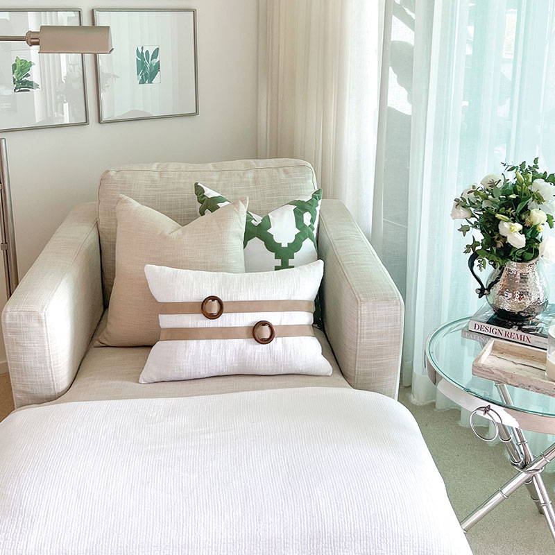 A white modern cushion featuring suede sashes with timber buckle.