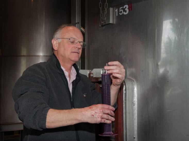 Chai du Domaine Constant-Duquesnoy : élevage en amphores d'argile et barriques bourguignonnes pour les cuvées Vinsobres. Jacky Blot se tient dans son chai à barriques au Domaine de la Taille aux Loups. Entouré de rangées de barriques en bois, il examine attentivement une de ses créations, symbolisant son engagement dans l'élevage long et soigné des vins.