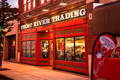 the old red wood and glass storefront of frost river in the evening