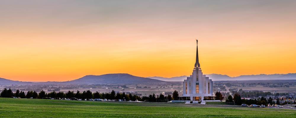 Panoramic Rexburg Temple picture featuring an orange sunset against purple mountains.