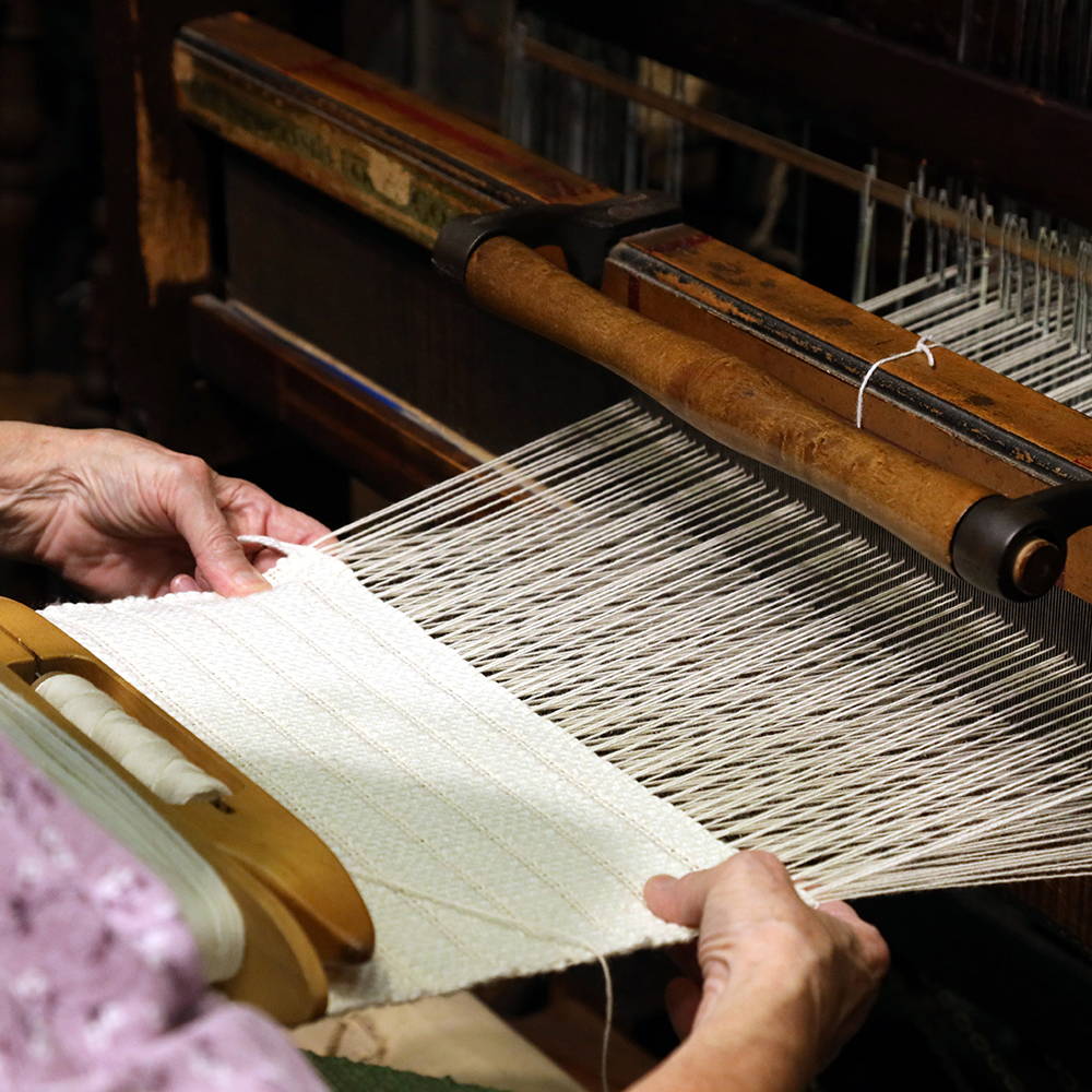 Woman artisan using a traditional loom to hand weave a textile fabric